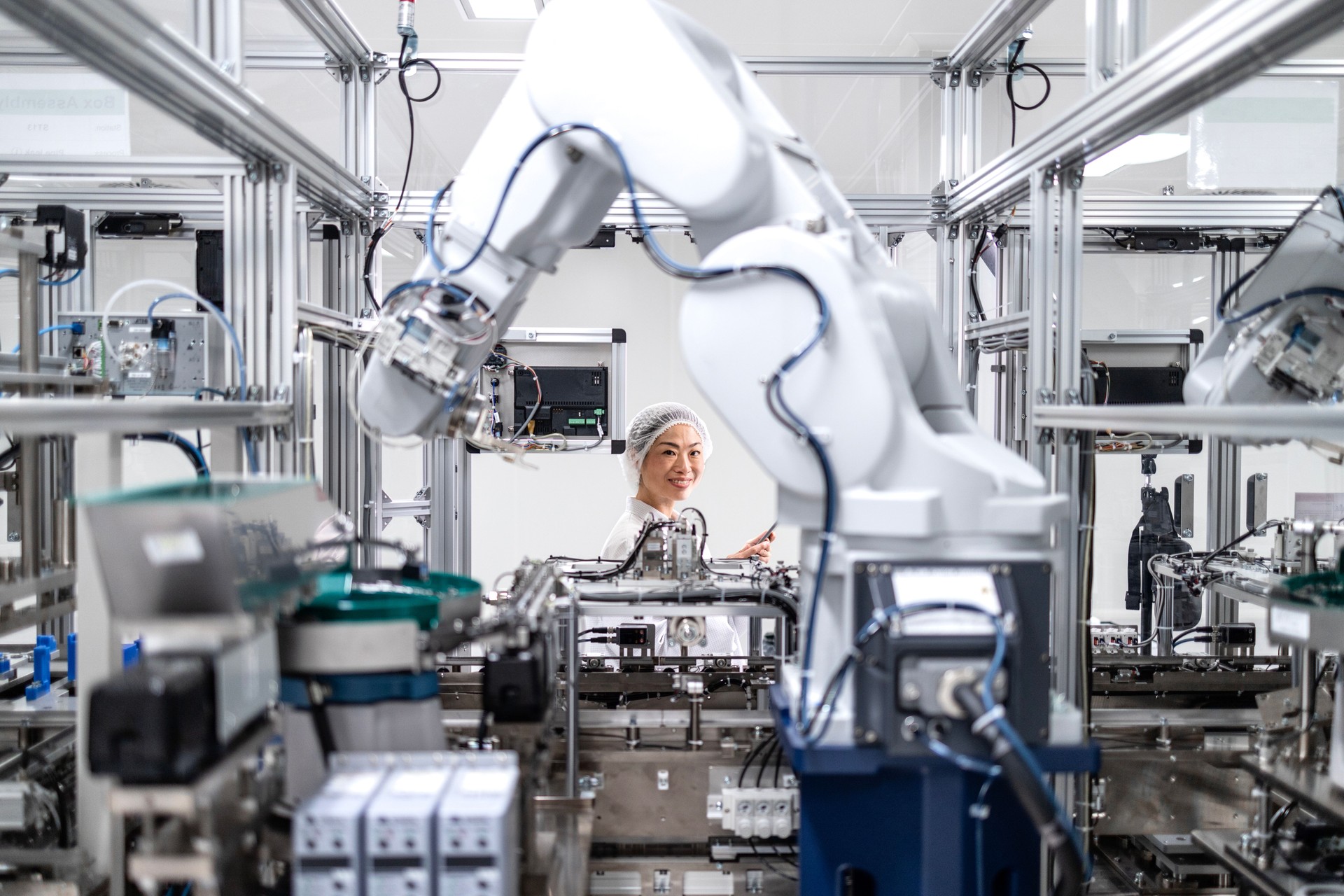 Technology engineer controlling robotic arm production process in electronics factory.