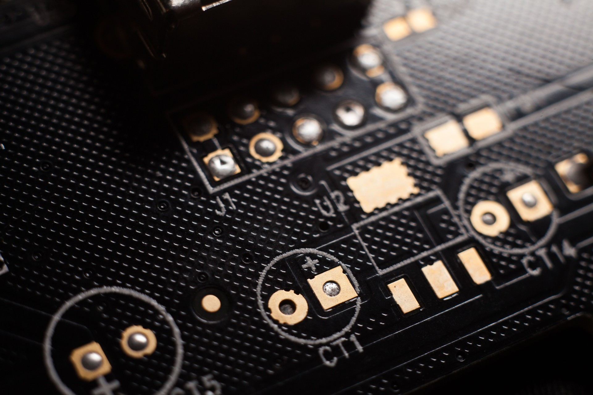 Macro photo of a black computer printed circuit board with selective focus on place for electronic components